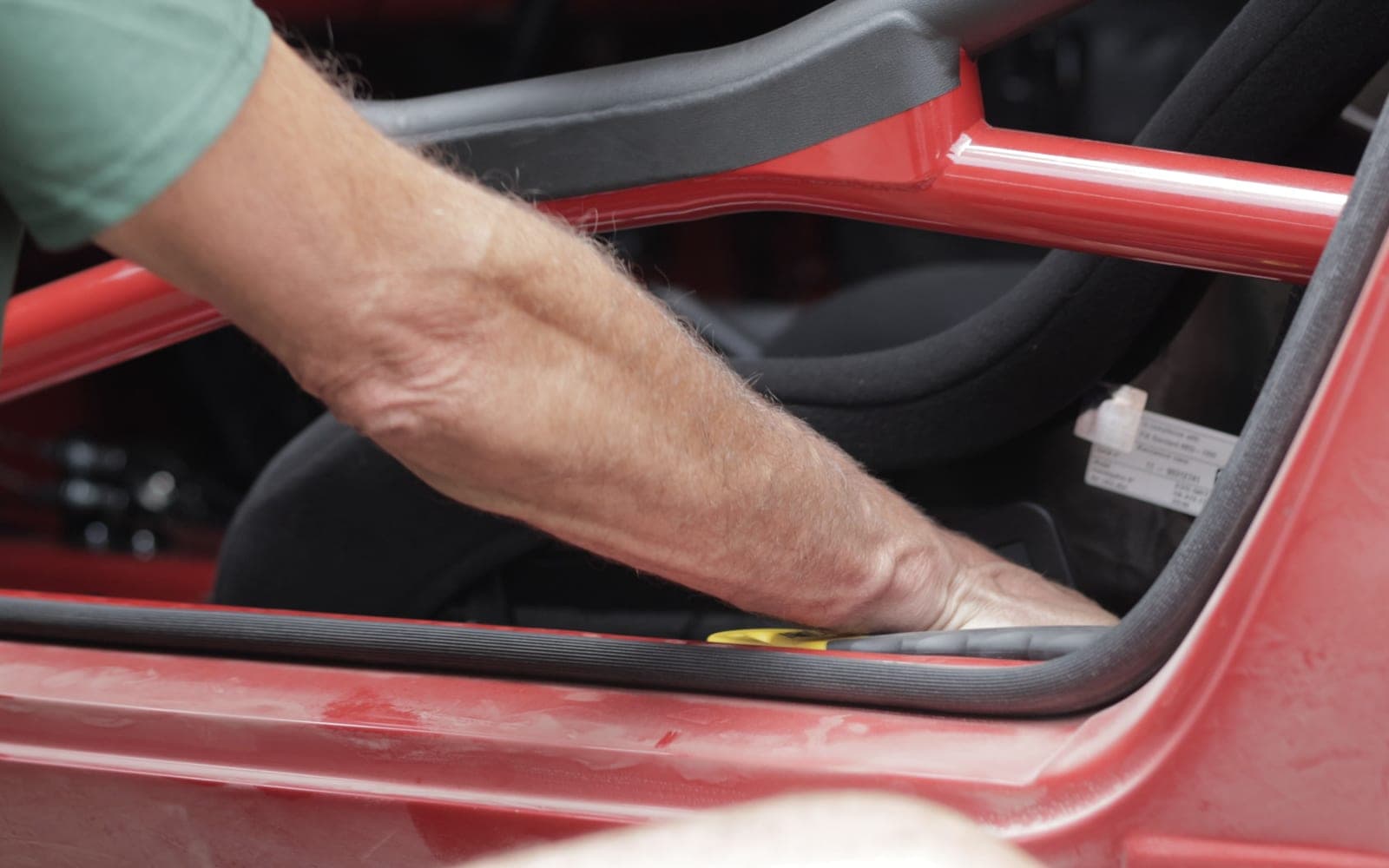 A mechanic's hand on the welded-in roll cage of the red Safari build